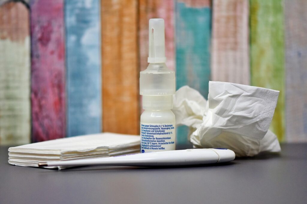 Nasal spray bottle beside tissues on a table, representing cold and congestion remedies