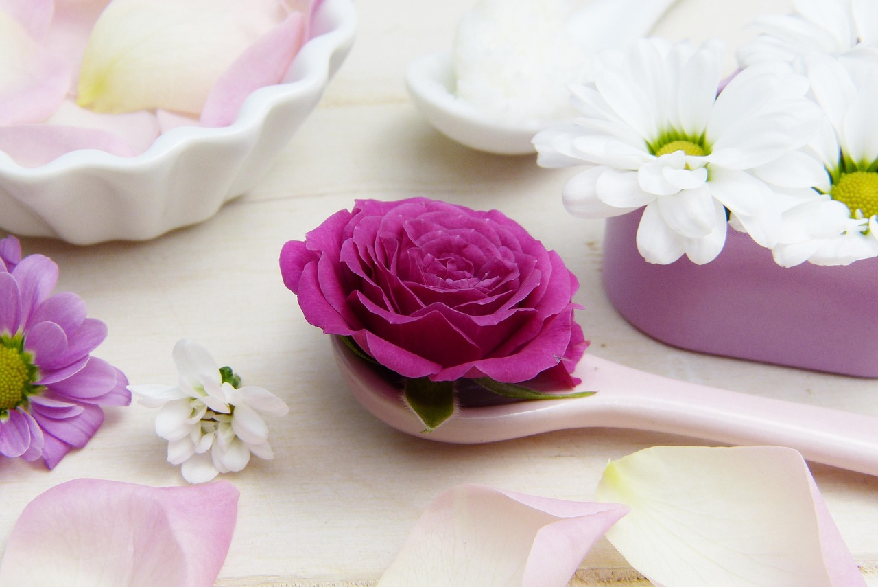 Pink spoon of shea butter cream with roses and daisies in a small bowl, representing retinoid and retinol creams in pregnancy