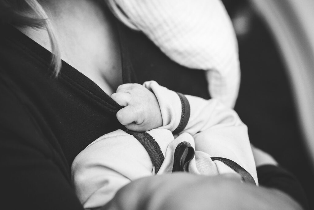 Mother cradling her baby against her chest in black and white, representing breastfeeding and retinol