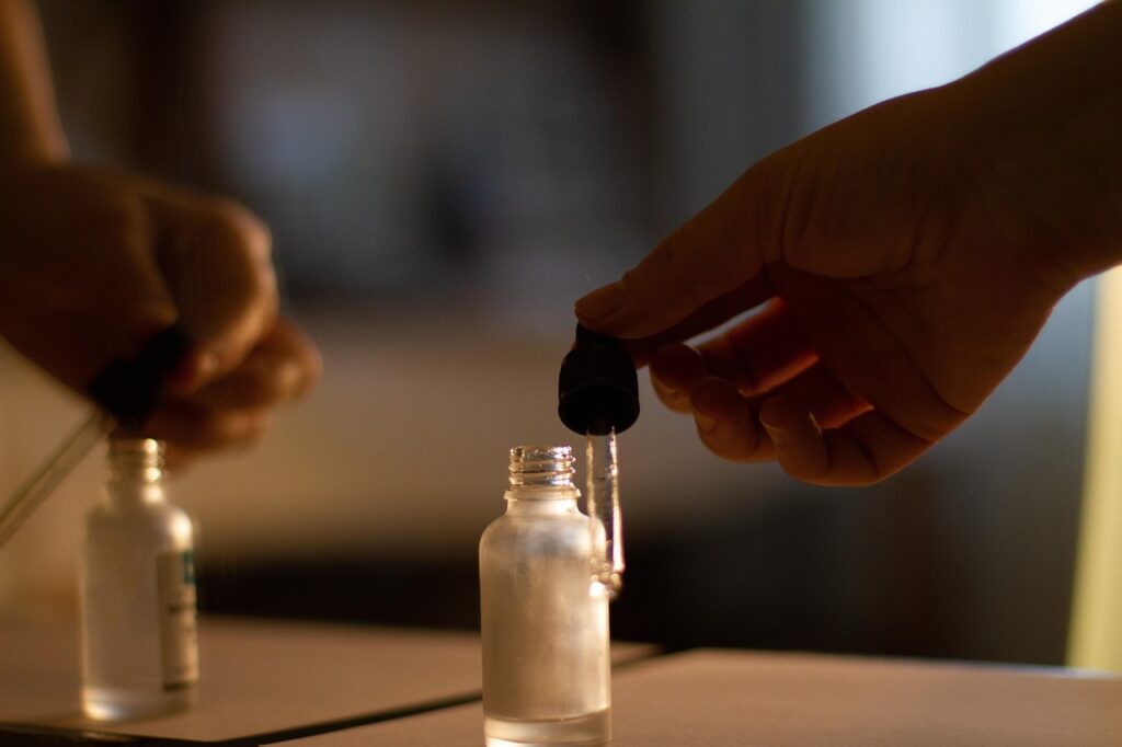 Glass dropper above a small skincare serum bottle in warm window light, representing retinol serum