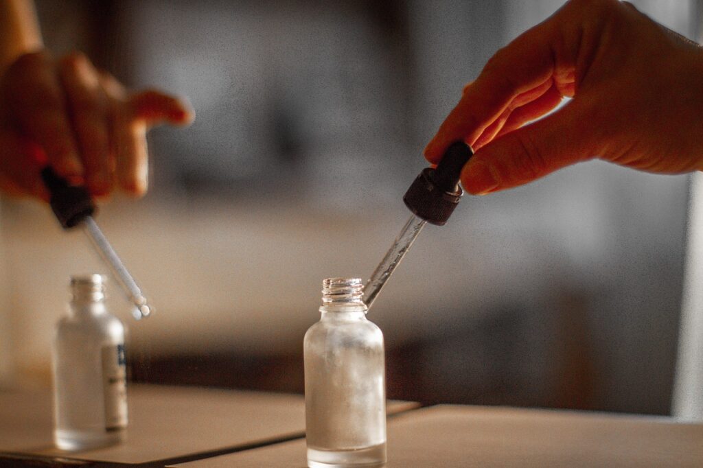 Dropper lifted from a small glass skincare bottle in soft light, representing retinyl palmitate serums