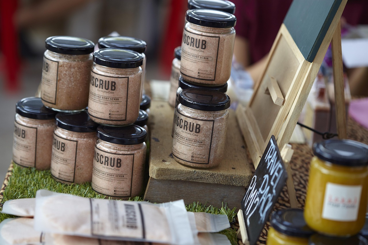 Stacked jars of body scrub with small printed labels on a market table, representing reading product labels