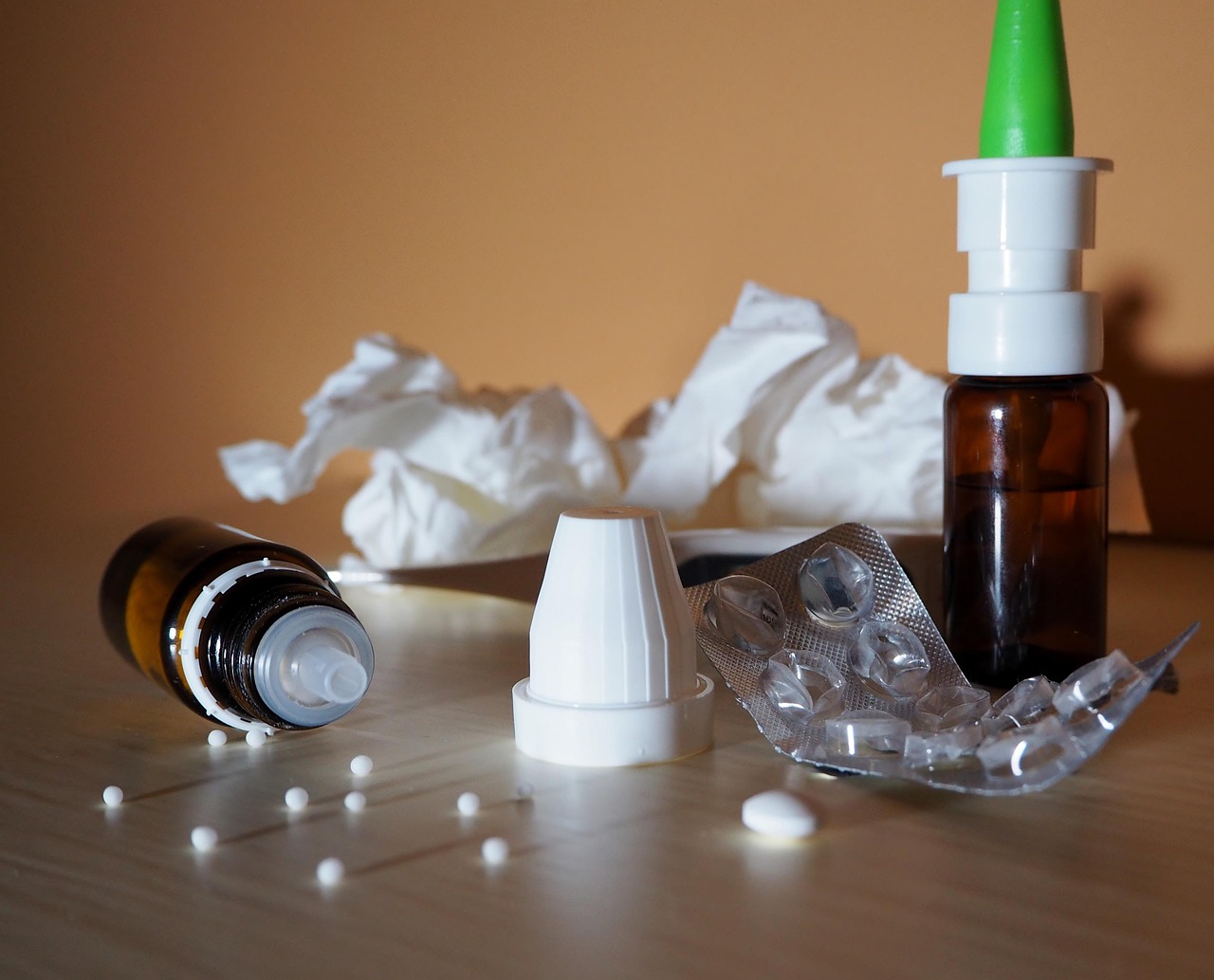 Nasal spray bottle, tissues and cold remedies on a table, representing decongestant options during pregnancy