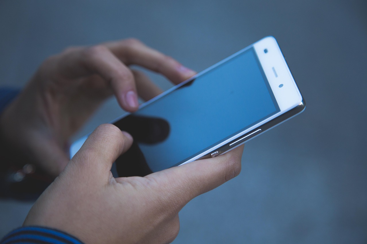 Hands holding a smartphone with a blank blue screen, representing troubleshooting an app that will not scan products