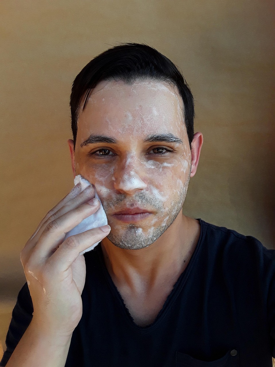 Young man washing his face, exploring skincare like SkinCeuticals C E Ferulic during pregnancy.