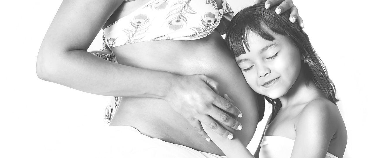 Black and white portrait of a pregnant mother and daughter, comparing pregnancy-safe retinol.