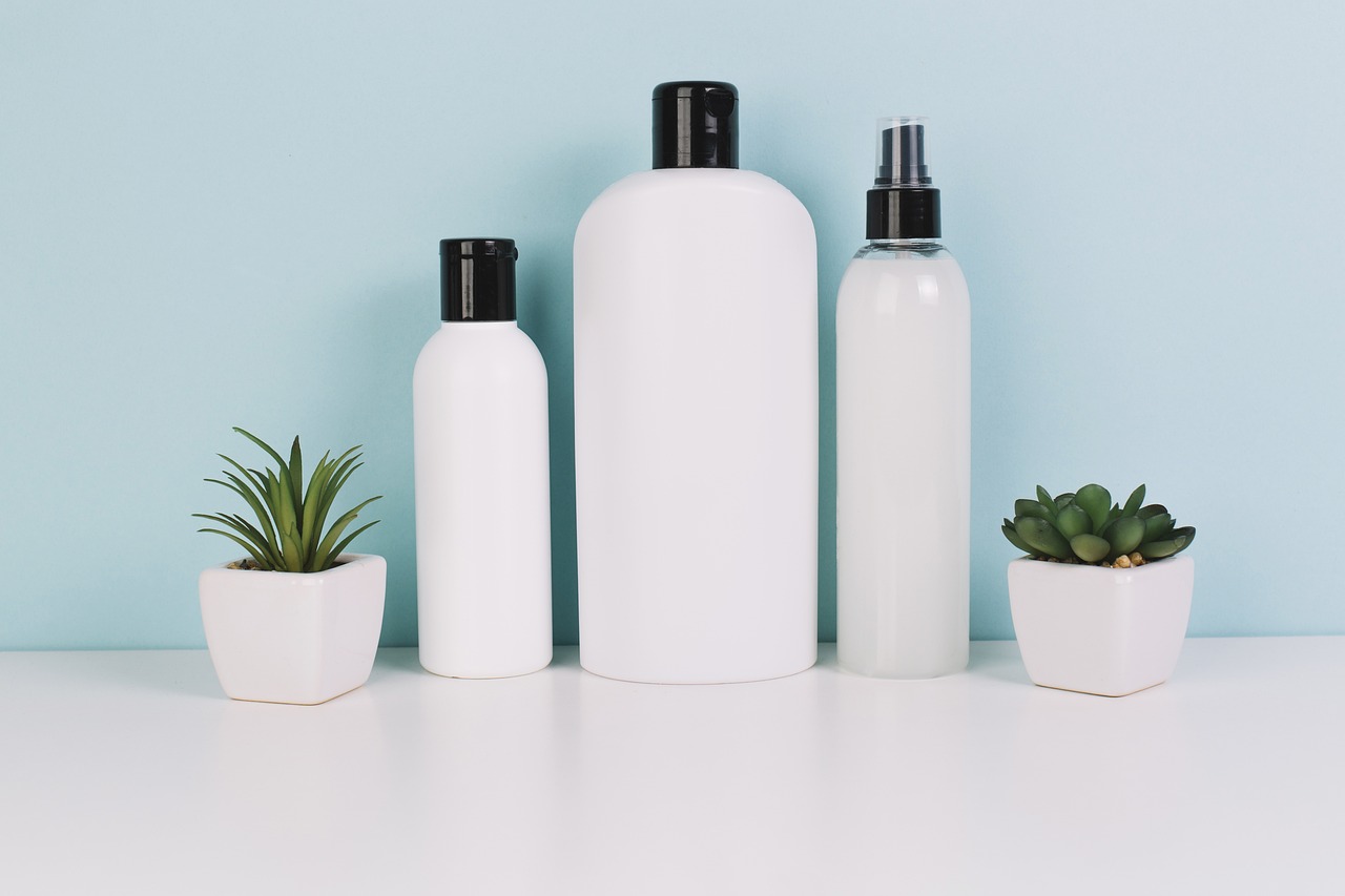 Row of plain white skincare bottles beside small succulent plants, representing choosing skincare brands in pregnancy