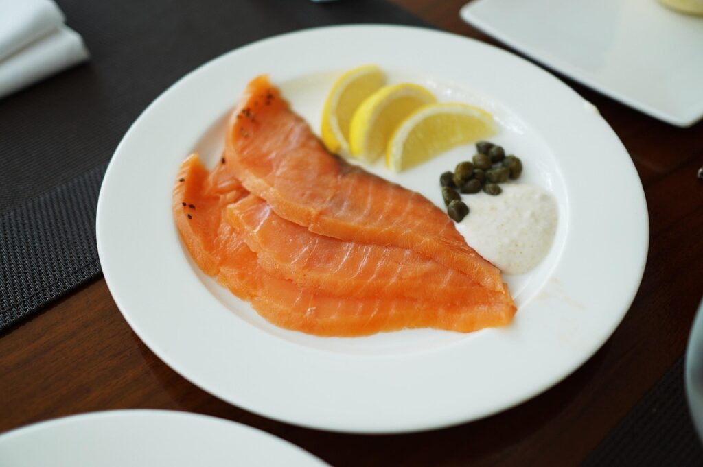 Plate of sliced smoked salmon with lemon wedges, capers and cream, relevant to eating lox while pregnant