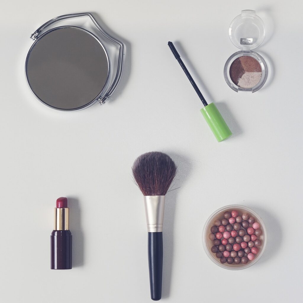 Flat lay of loose and pressed cosmetic powder with a makeup brush and lipstick, representing talc in cosmetics