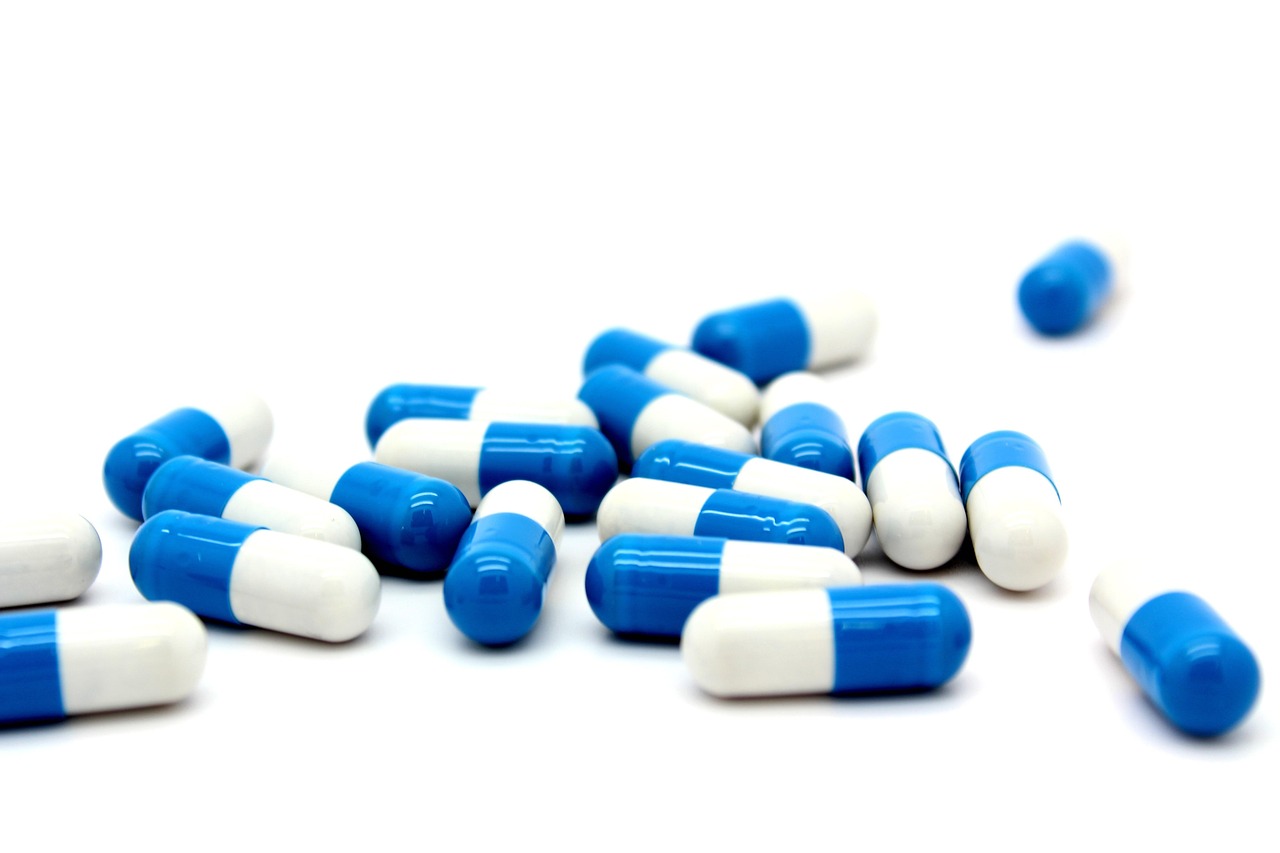 Blue and white medicine capsules scattered on a white background, representing iron pills, tablets and capsules
