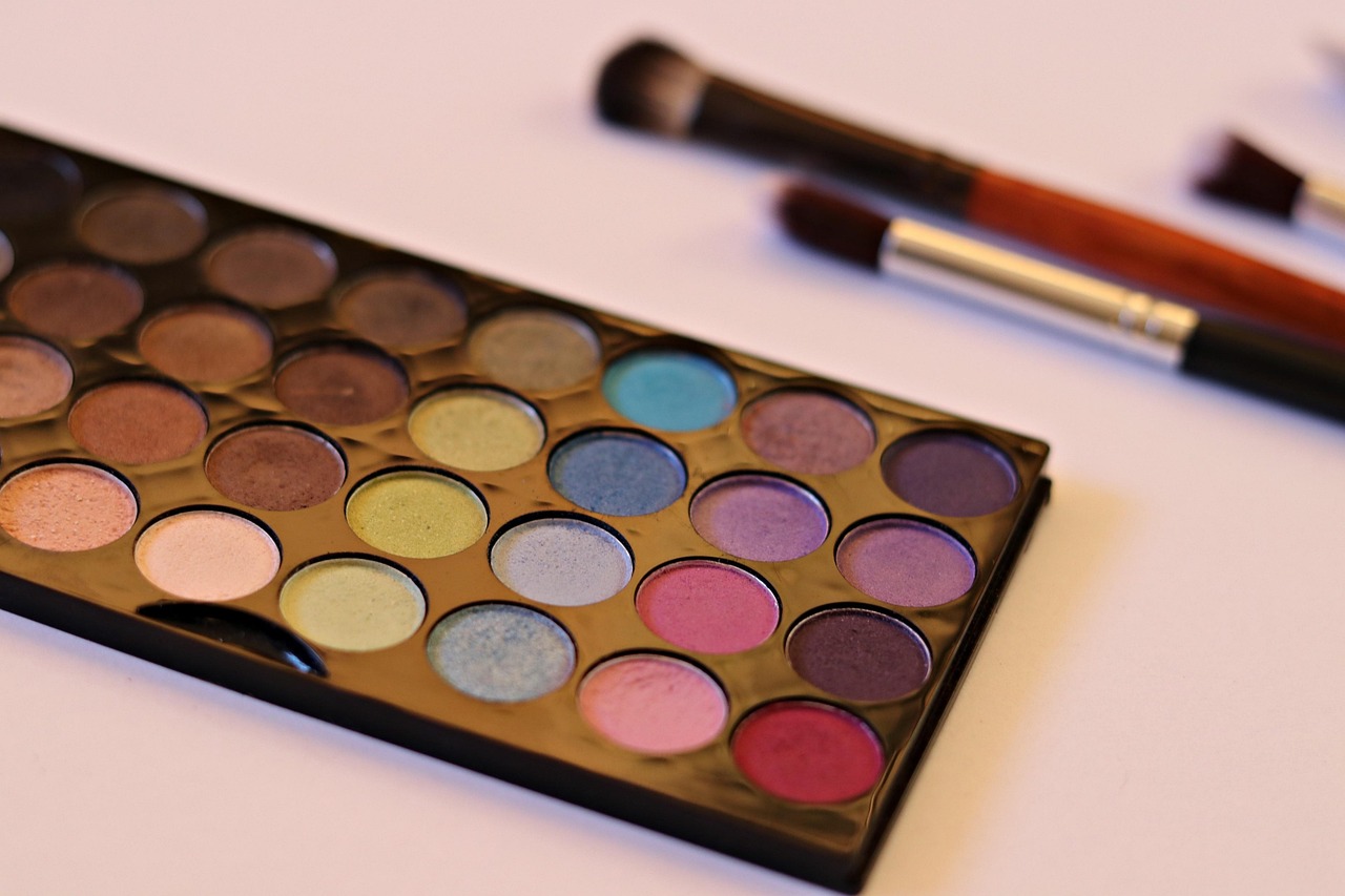 Eyeshadow palette with makeup brushes on a pale pink surface, representing checking makeup ingredients