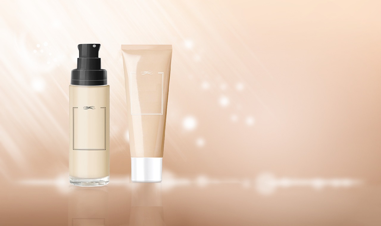 Pump bottle and tube of skincare products against a soft peach glowing background