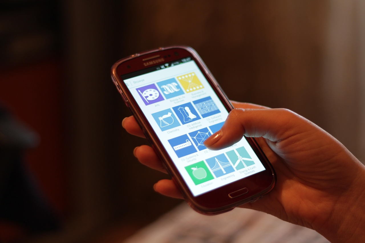 Hand holding a red smartphone displaying a grid of colorful app tiles, representing a product-scanning app review