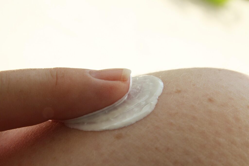 Sunscreen cream being rubbed into tanned skin, representing titanium dioxide mineral sun protection