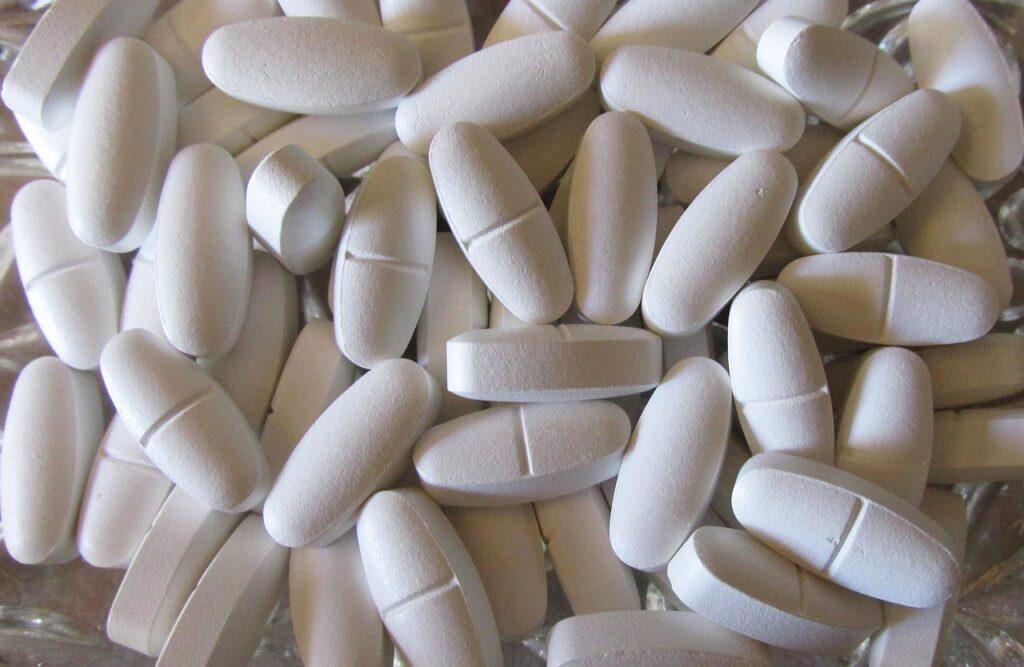 Pile of white oblong calcium tablets filling the frame, representing calcium carbonate antacid use during pregnancy