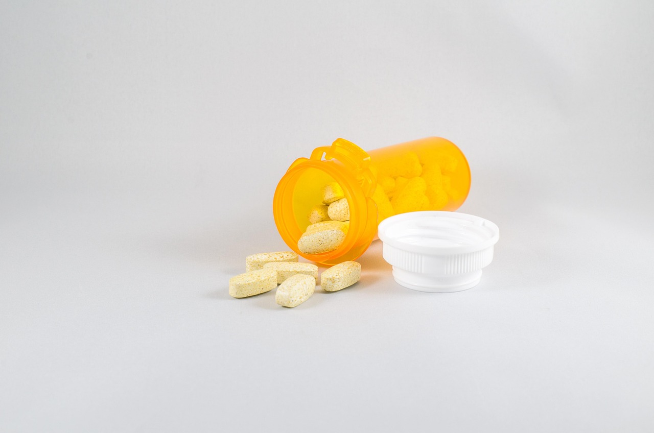 Orange prescription-style bottle with pale tablets spilling onto a gray surface, representing acetaminophen use in pregnancy