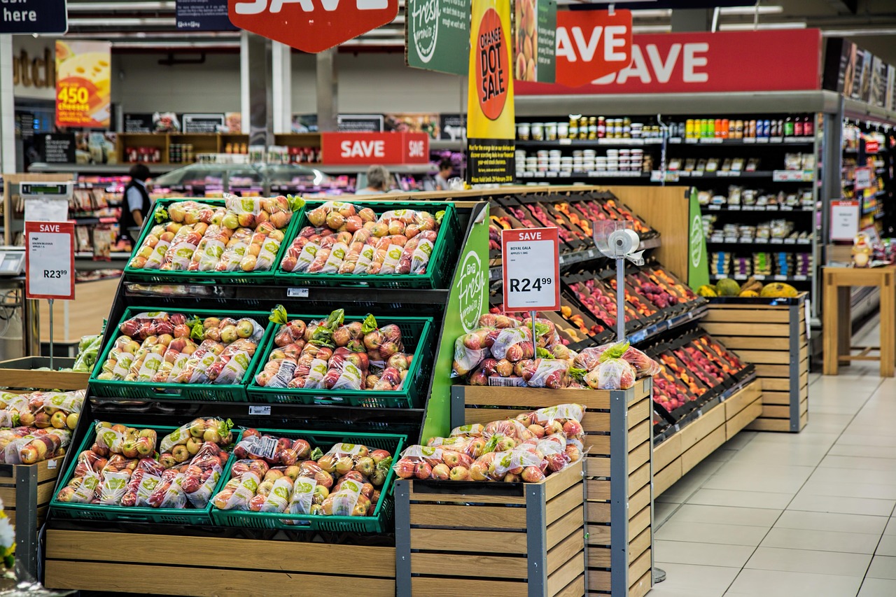 Supermarket aisle with crates of fresh fruit and price signs, representing analyzing product ingredients