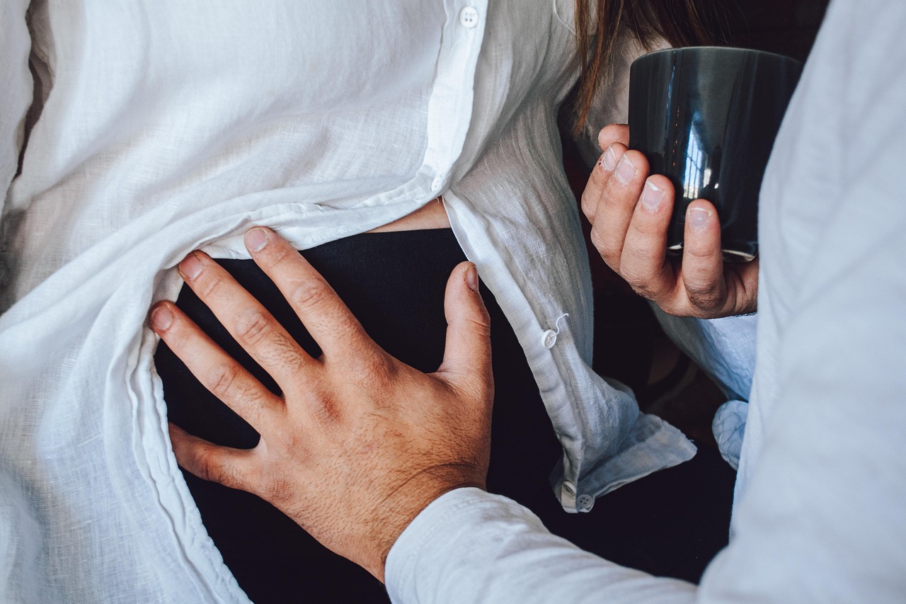Partner's hand resting on the lower back of a pregnant woman, representing back pain in pregnancy