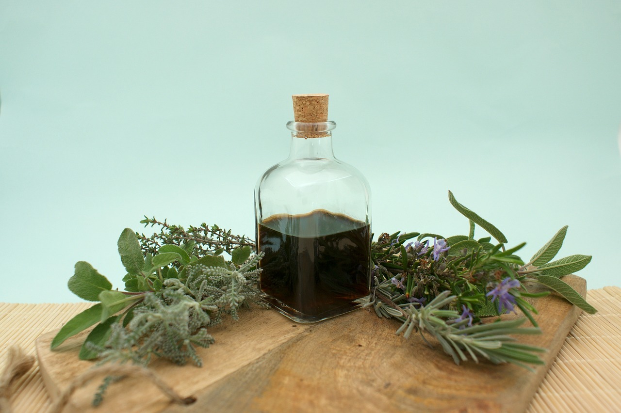 Glass bottle of herbal oil surrounded by fresh herbs on a wooden board, representing natural products in pregnancy
