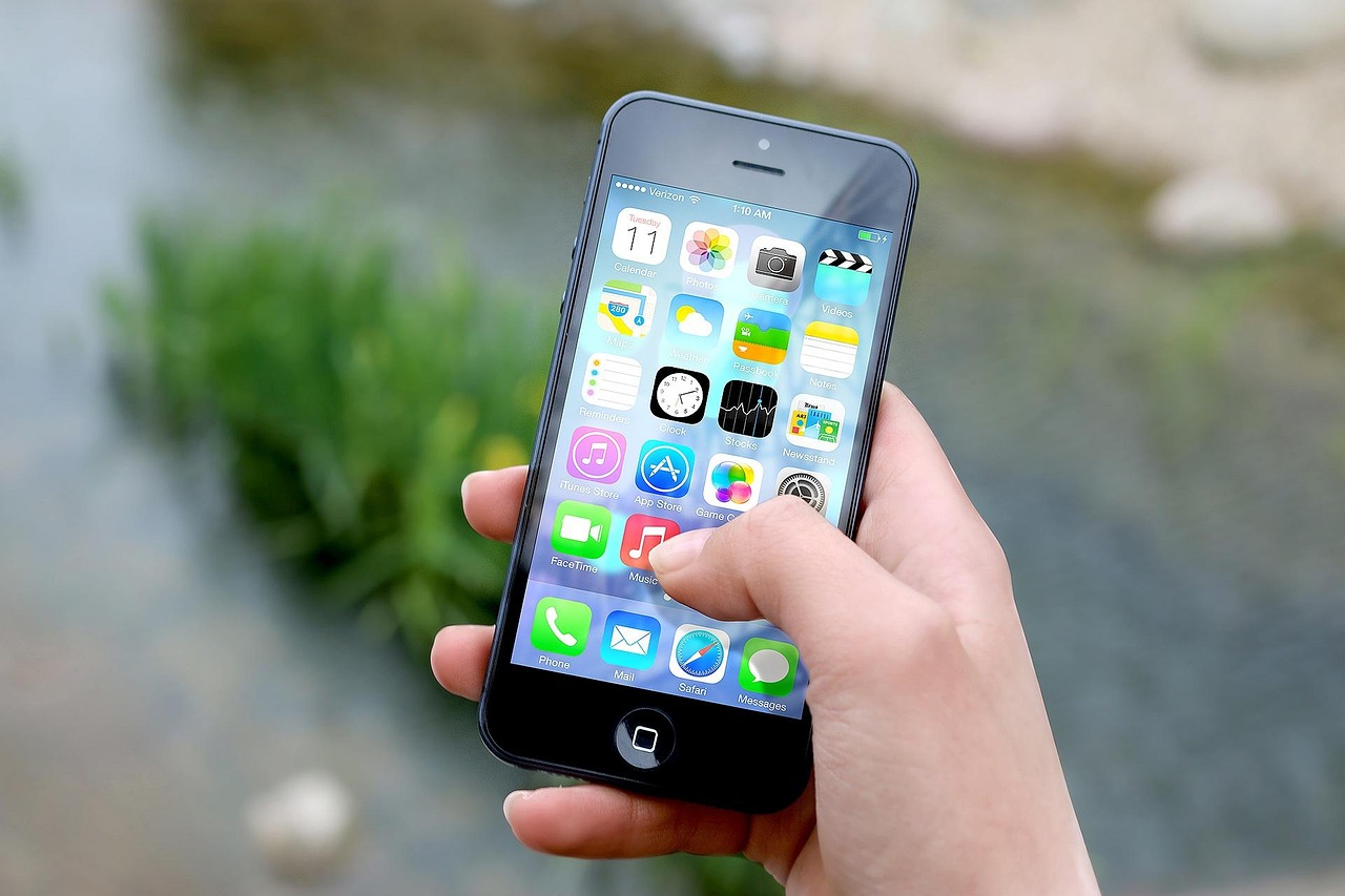 Hand holding a smartphone showing a screen of colorful app icons, representing a product-scanning app