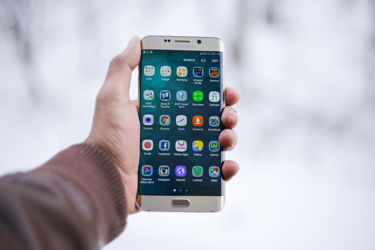 Hand holding a smartphone showing a grid of app icons, representing a product-scanning app profile