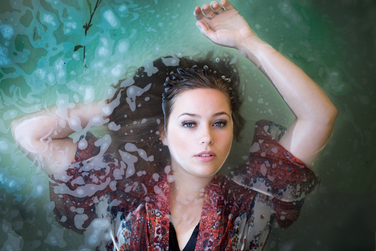 Wet portrait of a young woman floating in water, embodying the gentle safety of colloidal oatmeal for pregnancy.