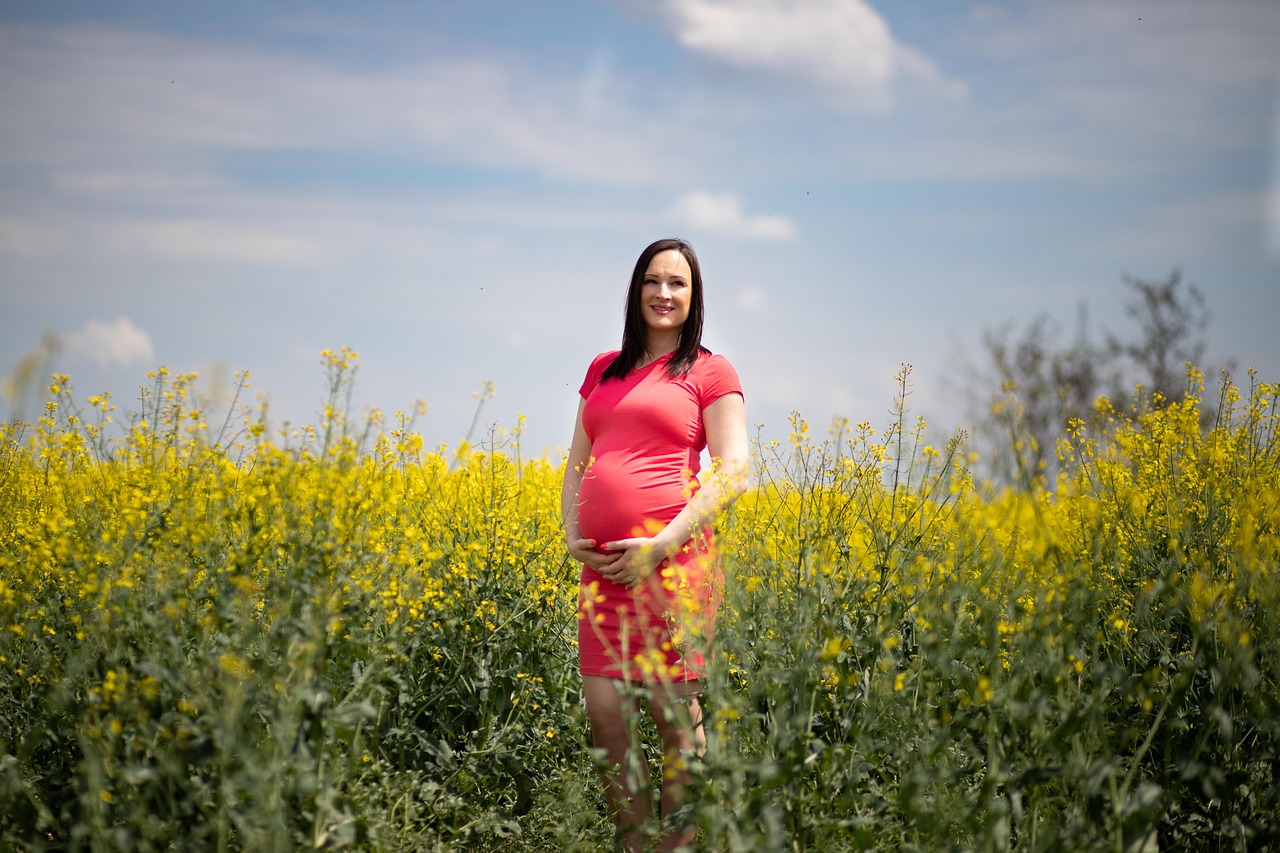 Pregnant woman outdoors, gently touching her belly, exploring jojoba oil's safety during pregnancy.