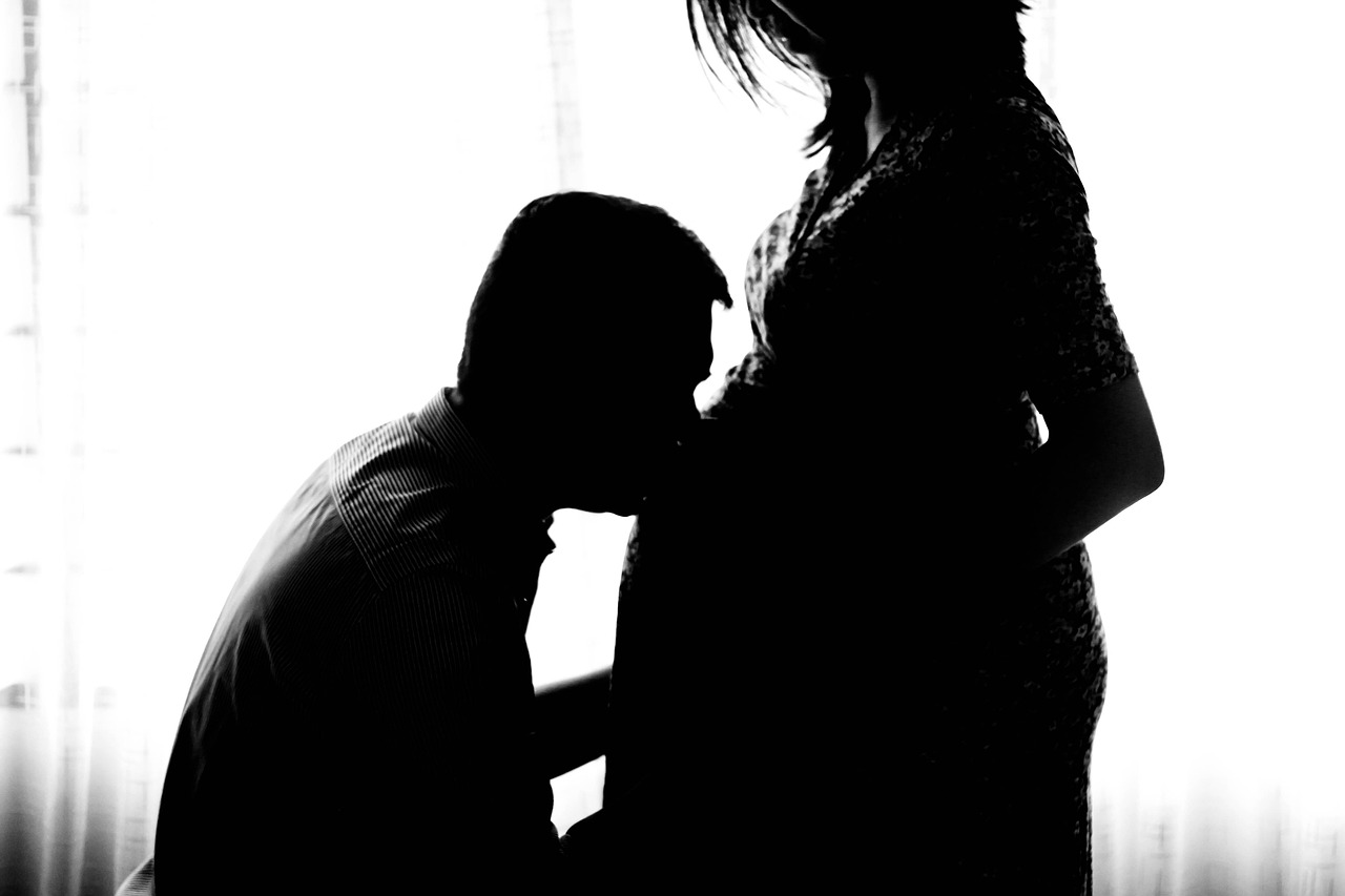 A pregnant woman kisses her baby bump, considering Oscar Mayer safety during pregnancy.