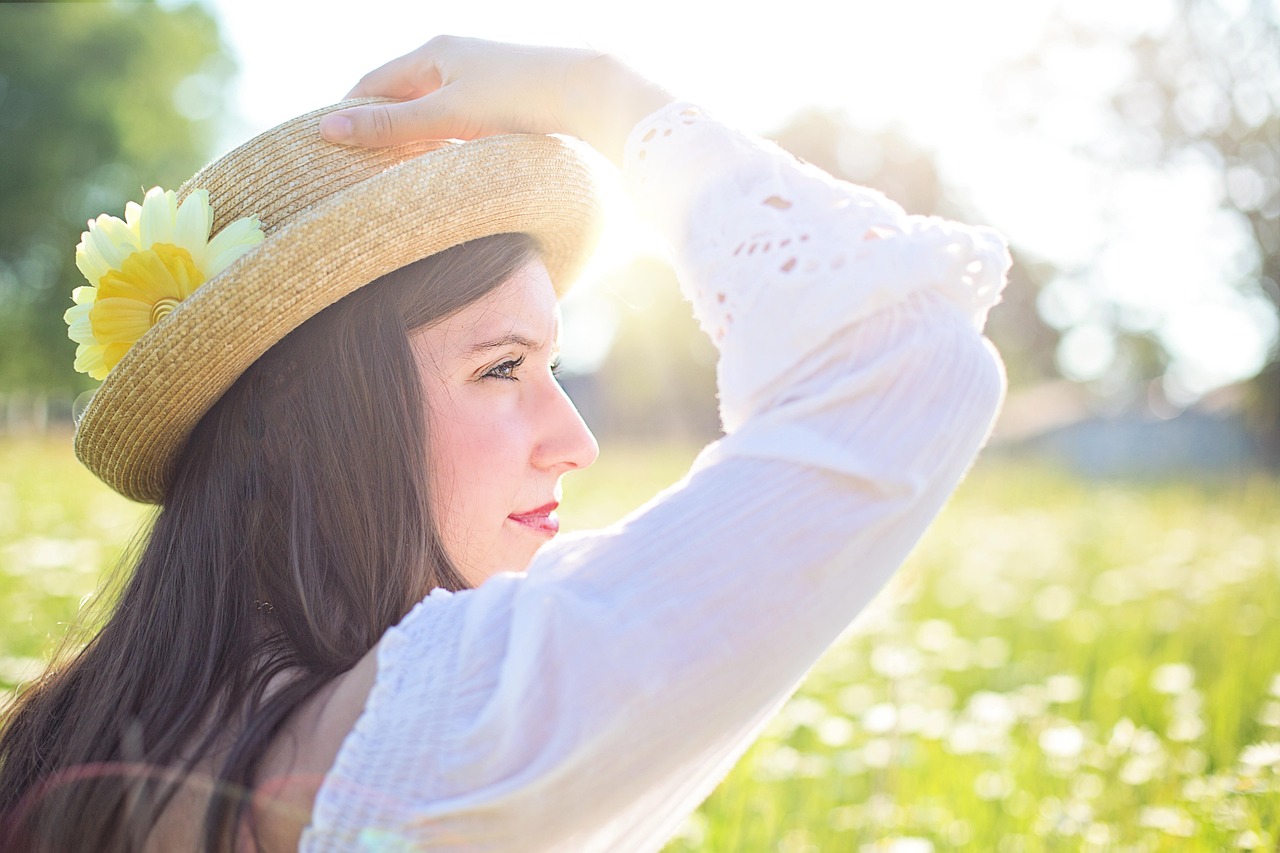 Woman in a hat in a sunny field, considering tea tree oil safety during pregnancy.